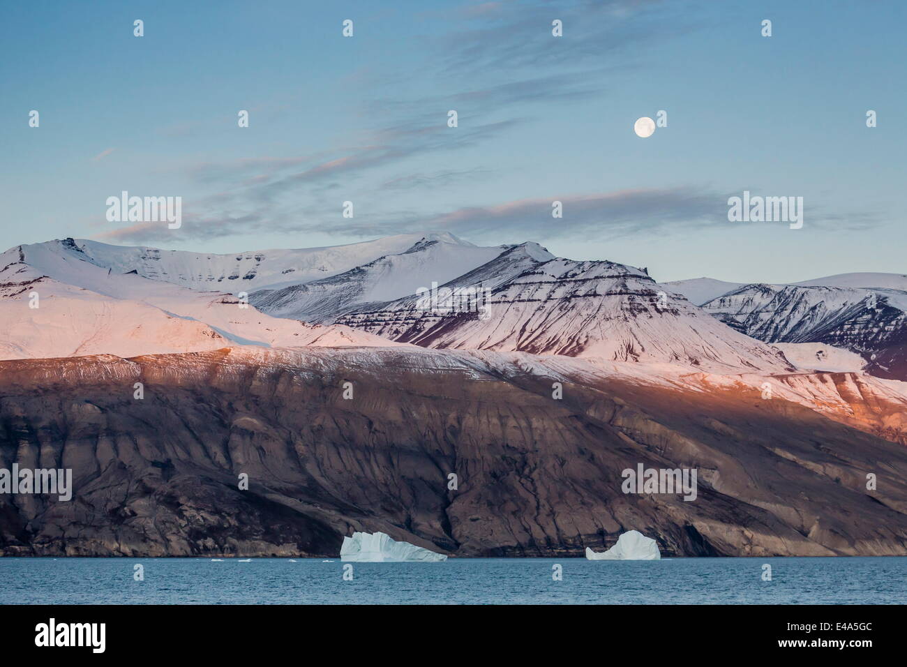 Luna quasi piena impostazione nelle prime ore del mattino nei pressi di Qilakitsoq, Groenlandia, regioni polari Foto Stock