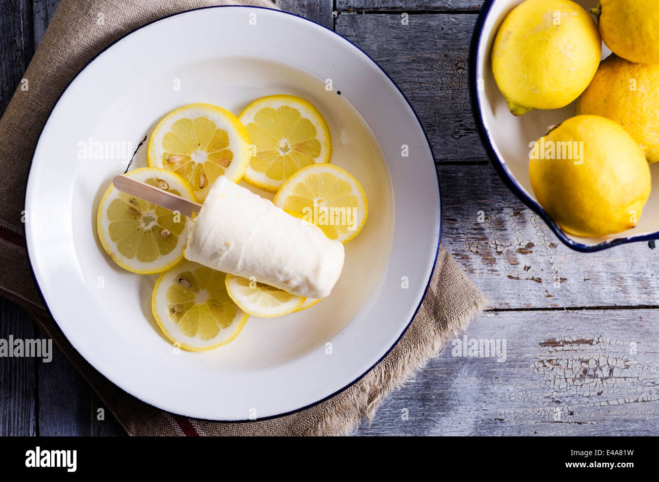 Ciotola di limoni e piastra di fatti in casa a base di crema di limone per lecca-lecca di ghiaccio su fette di limone, vista in elevazione Foto Stock