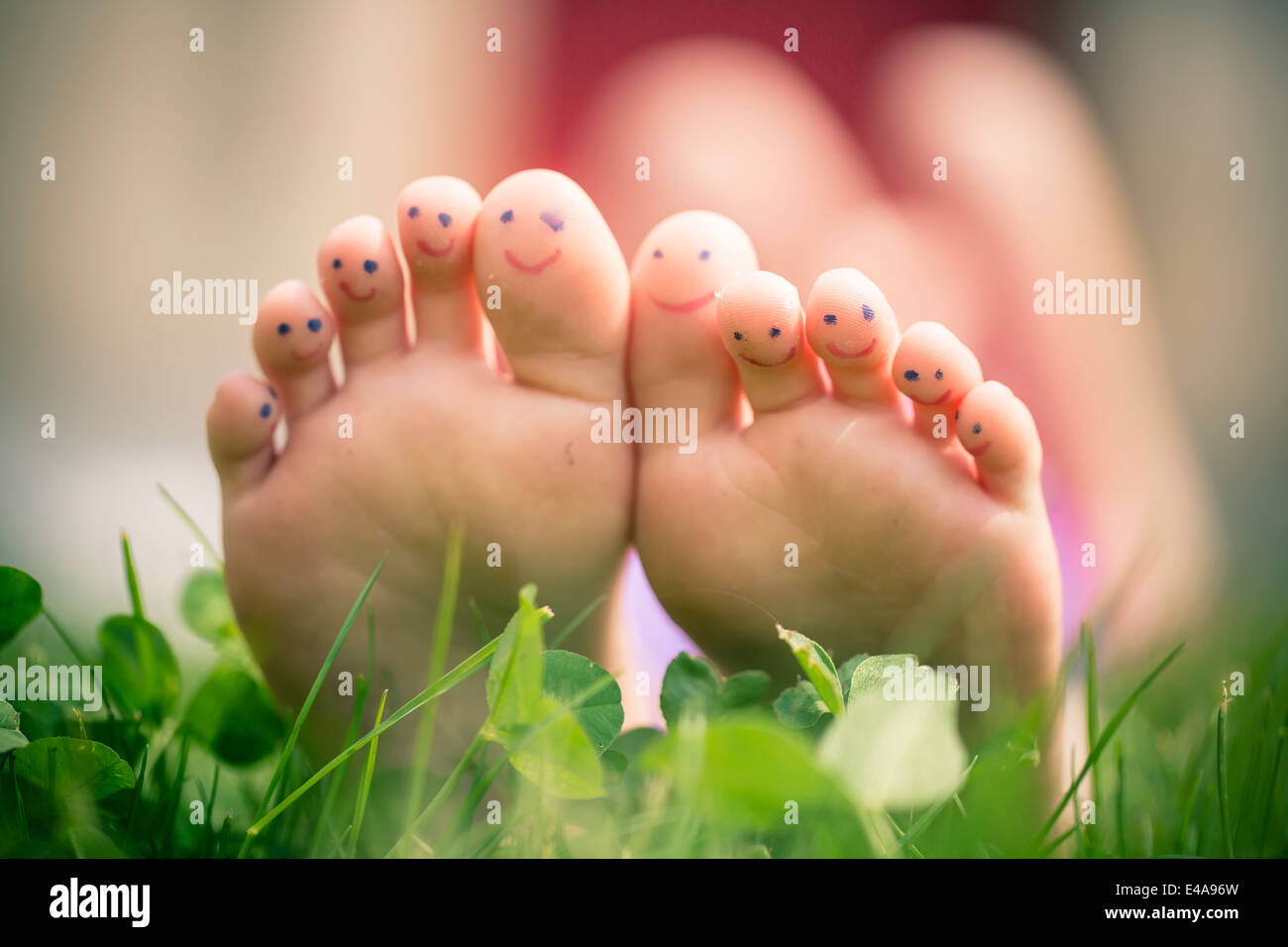 Poco ragazza in piedi con il dipinto di dita giacente in erba Foto Stock