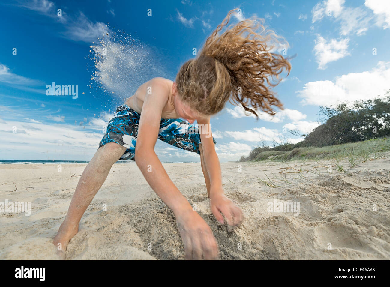 Australia, Nuovo Galles del Sud, Pottsville, ragazzo di scavare nella sabbia sulla spiaggia Foto Stock