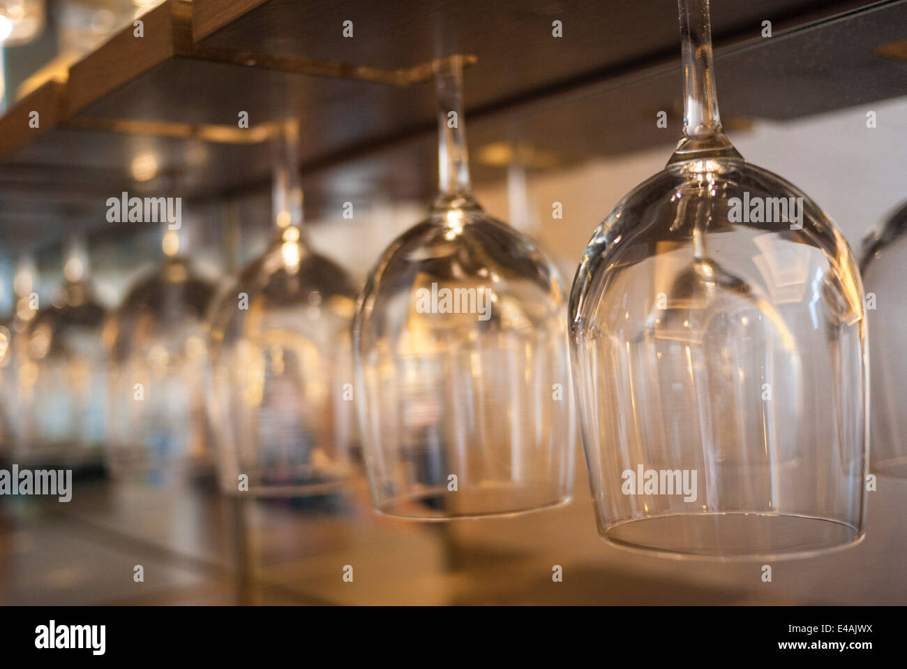 Una fila di vetro del vino appeso a testa in giù Foto Stock