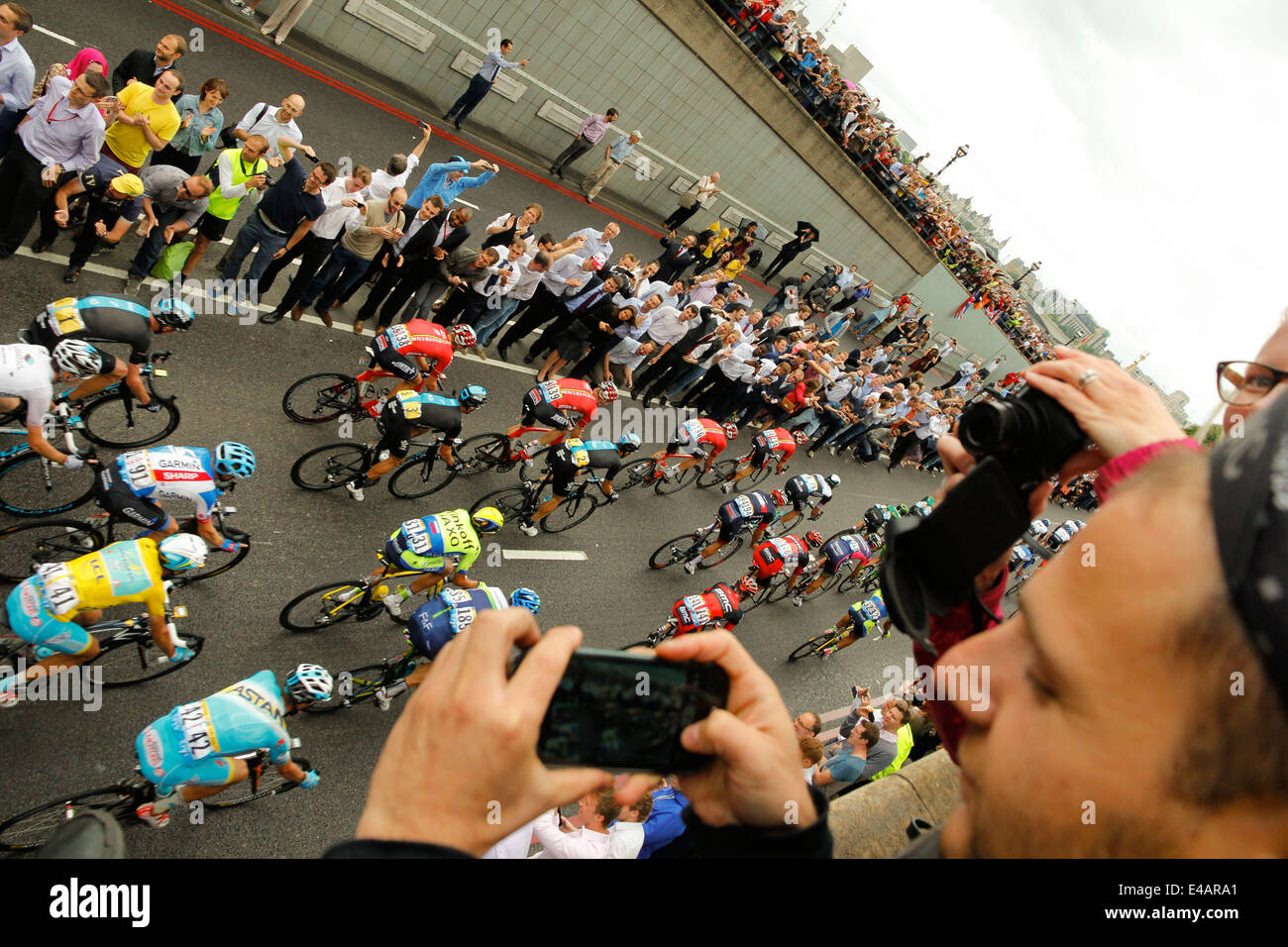 London, Regno Unito - 7 Luglio 2014: Il Tour de France peleton emergente dal Blackfriars sottopasso nella parte anteriore dei lavoratori della città utilizzando le telecamere. Foto Stock