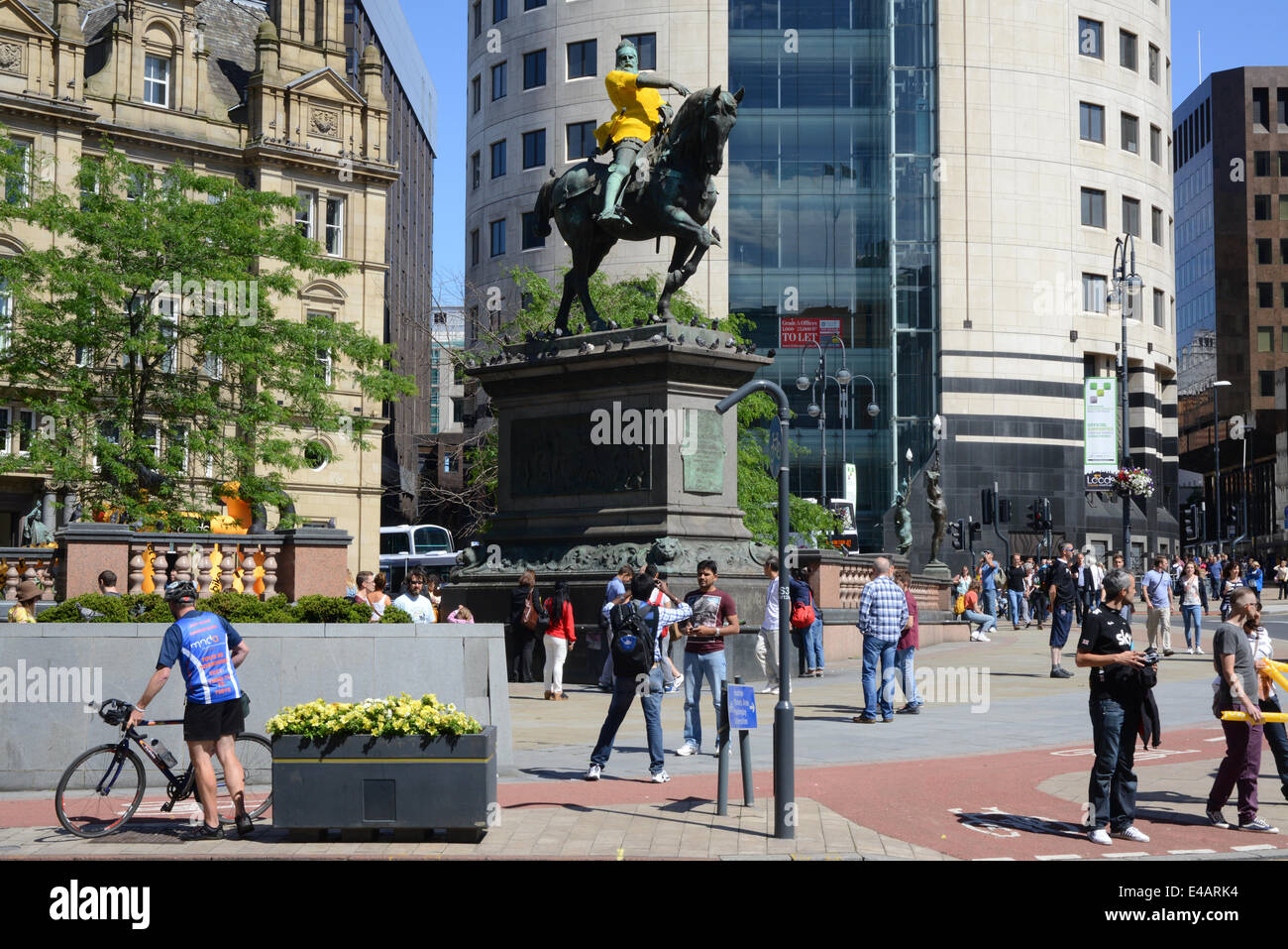 Spettatori passando il principe nero statua indossa maglia gialla che segna l'inizio del tour de France a Leeds Yorkshire Regno Unito Foto Stock