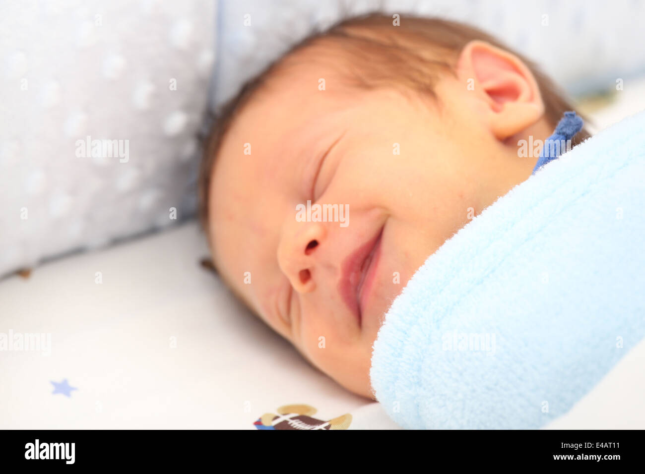 Una coperta che copre un neonato sorridente. Focus sulla coperta. Foto Stock