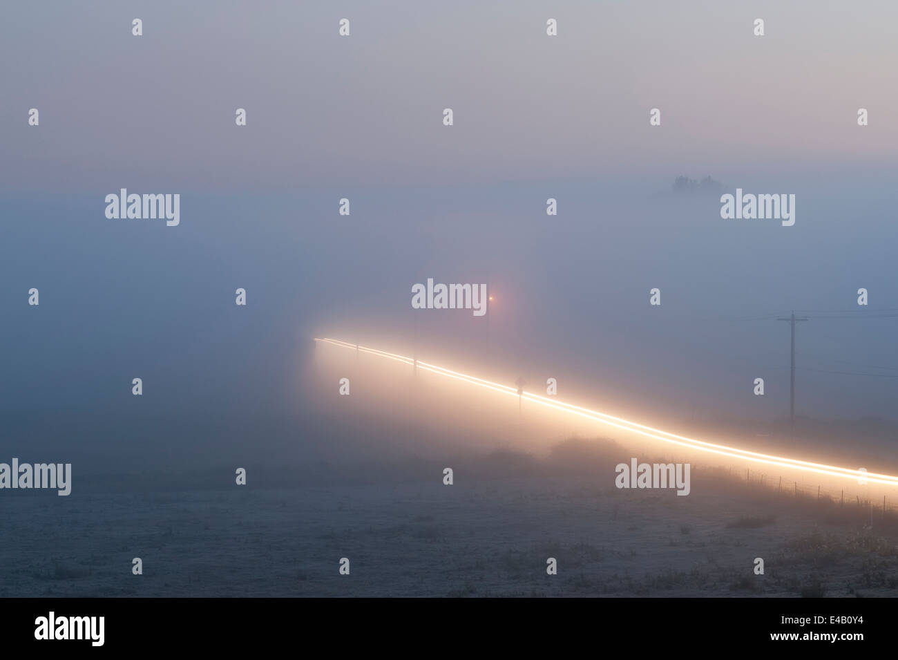 Valley nebbia con auto sentieri di luce sulla strada rurale Foto Stock