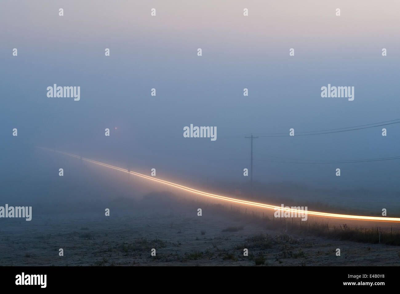 Valley nebbia con auto sentieri di luce sulla strada rurale Foto Stock