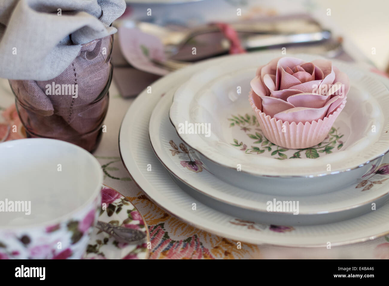 Whimsical luogo impostazione con zucchero tortina di rose su vintage in Cina. Dolce e romantica di dettaglio tea party tabella. Foto Stock