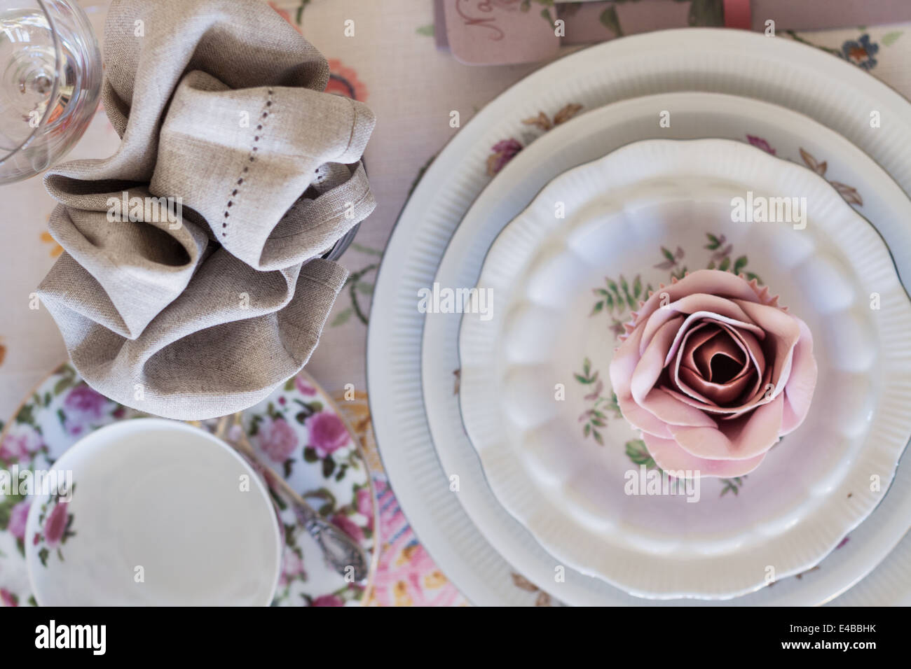 Whimsical luogo impostazione con zucchero tortina di rose su vintage in Cina. Dolce e romantica di dettaglio tea party tabella. Foto Stock