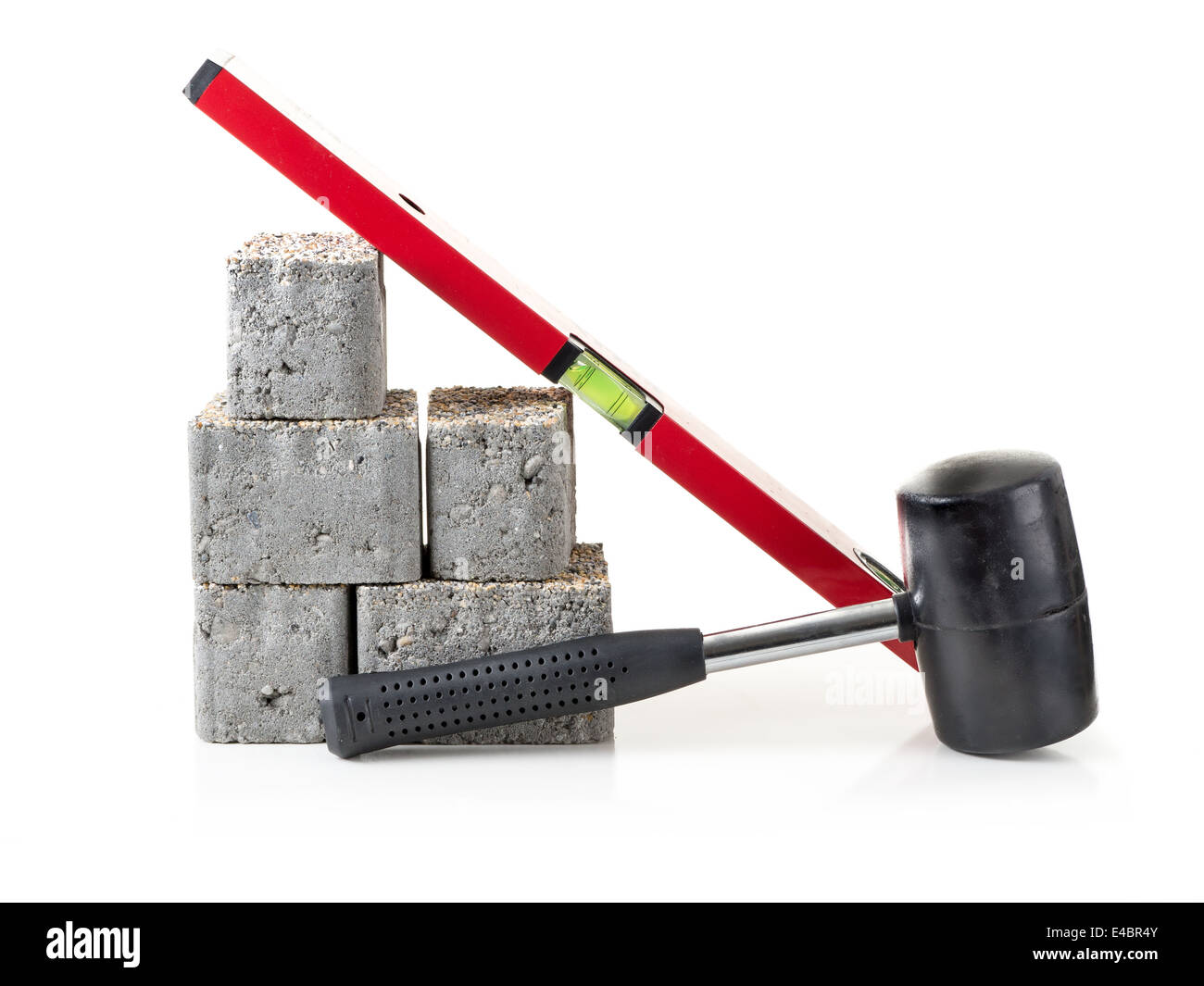 Pavimentazione in calcestruzzo blocchi con un mazzuolo e livello di spirito shot su bianco Foto Stock