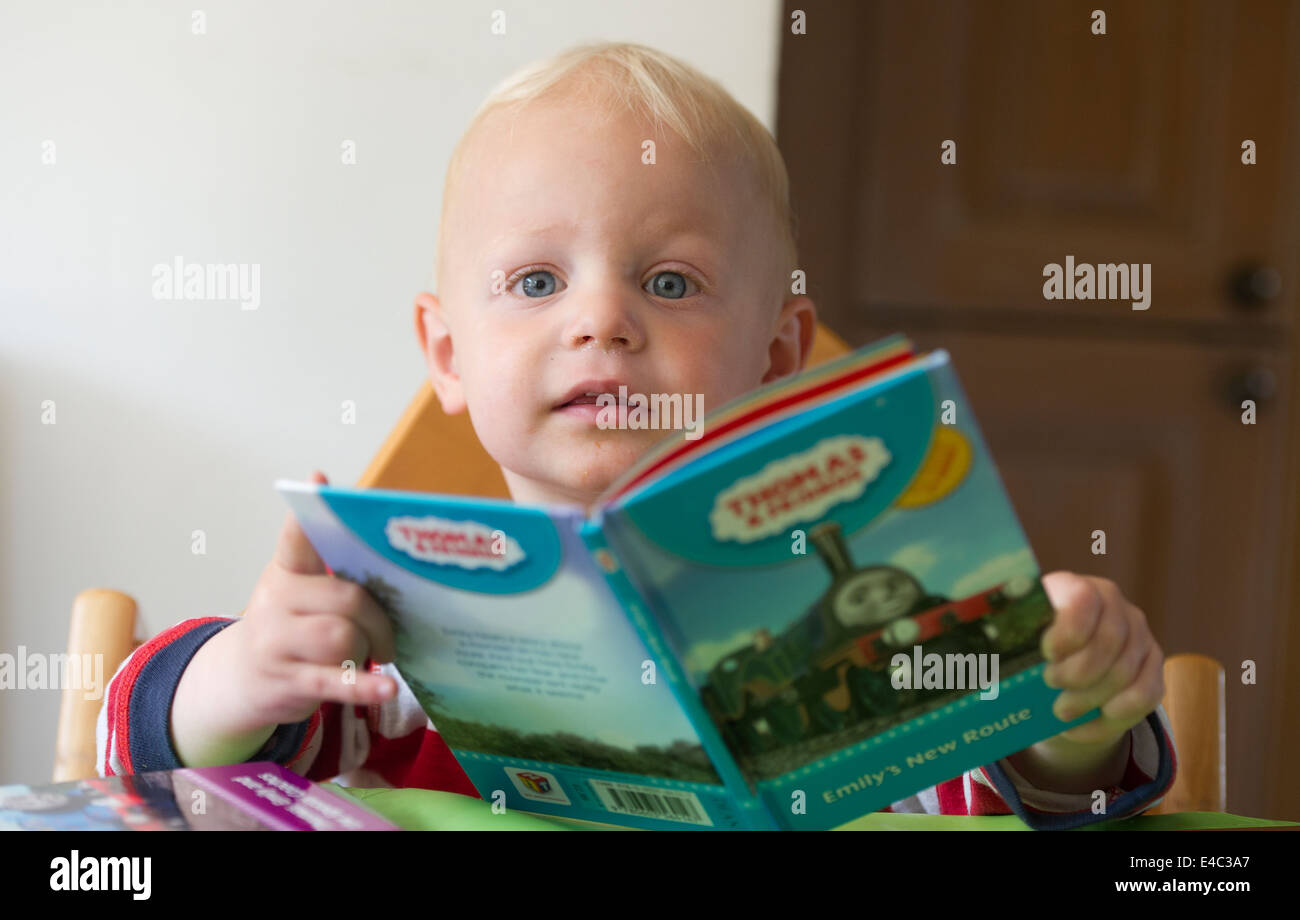 Un giovane ragazzo bambino la lettura di un libro Foto Stock