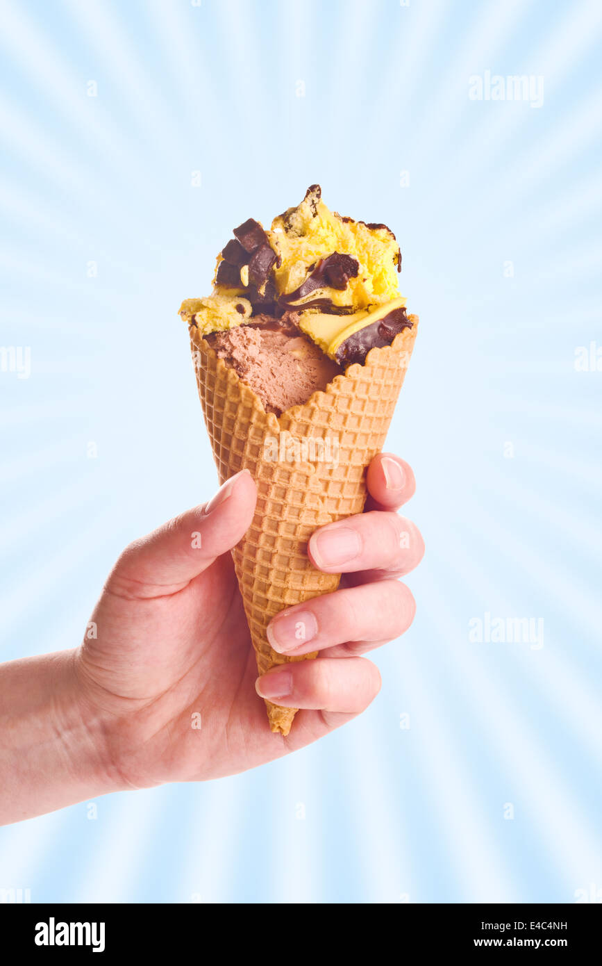 Donna mano che tiene il gelato al cioccolato in un cono. Foto Stock
