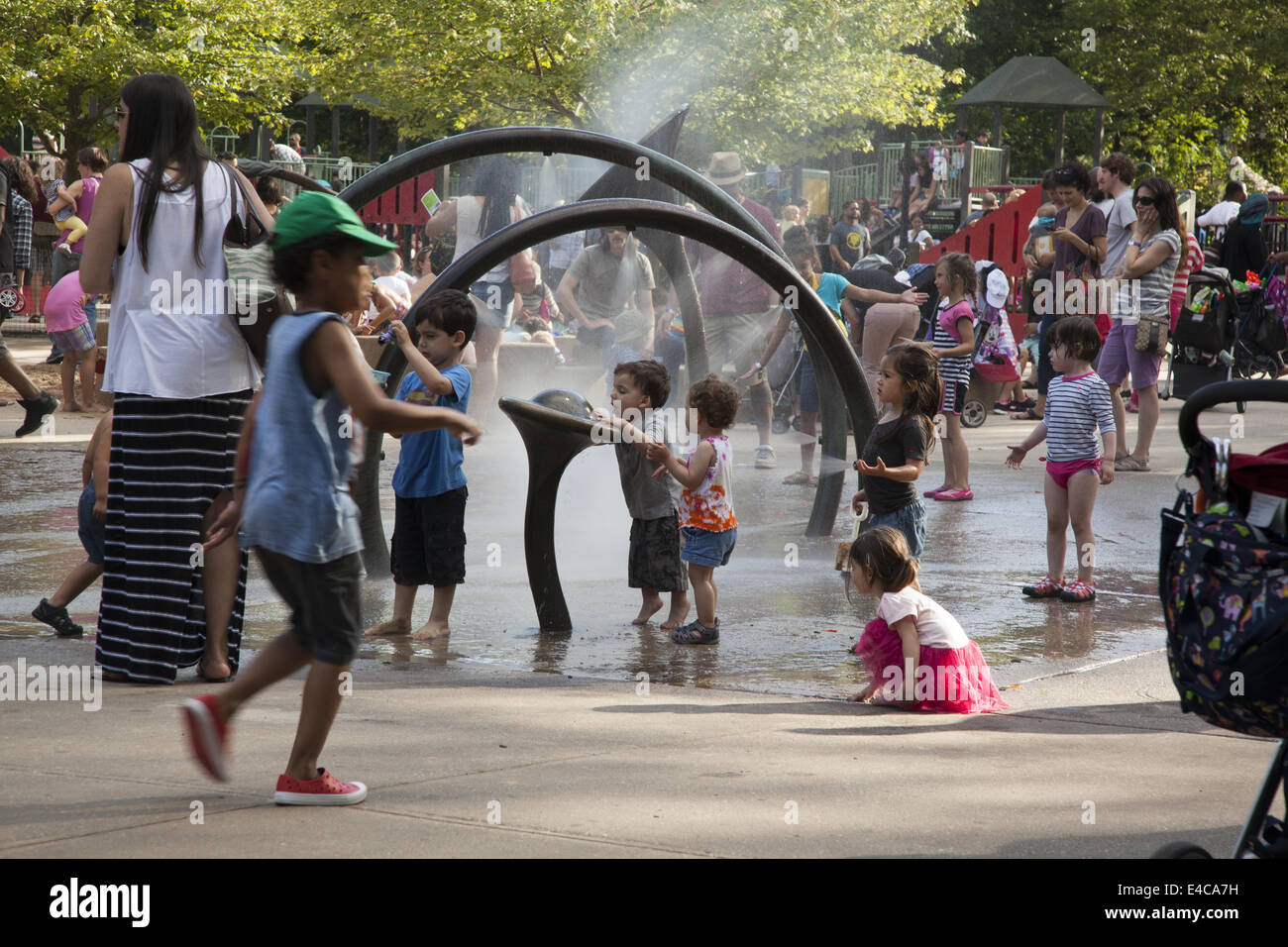 Bambini rinfrescarvi con l'acqua le irroratrici a Xi San Parco Giochi nel Prospect Park di Brooklyn, New York. Foto Stock