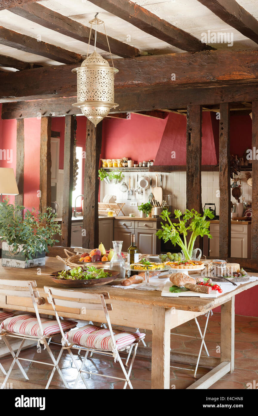 Tavola apparecchiata in grandi francese rustica cucina di paese con le vecchie travi a soffitto Foto Stock