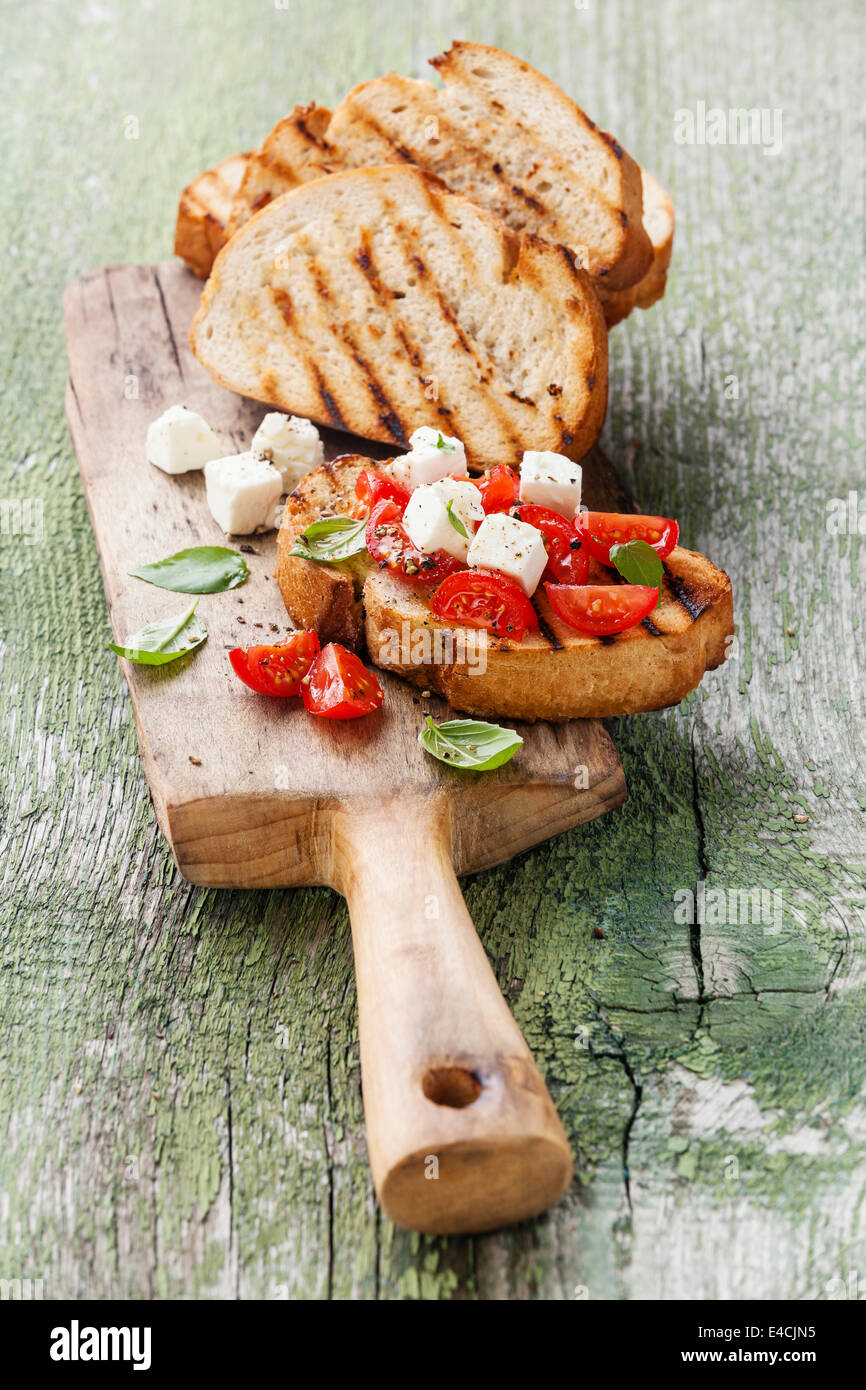 Italian bruschetta con pomodori tritati, il basilico e il formaggio su grigliate di crosta di pane Foto Stock