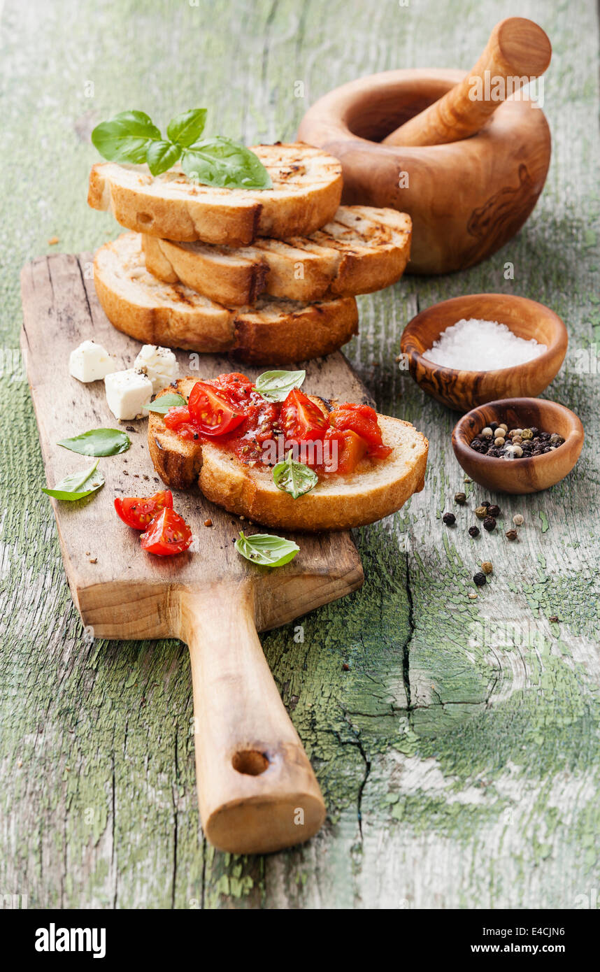 Italian bruschetta con pomodori a pezzi, basilico e olio su grigliate di crosta di pane Foto Stock