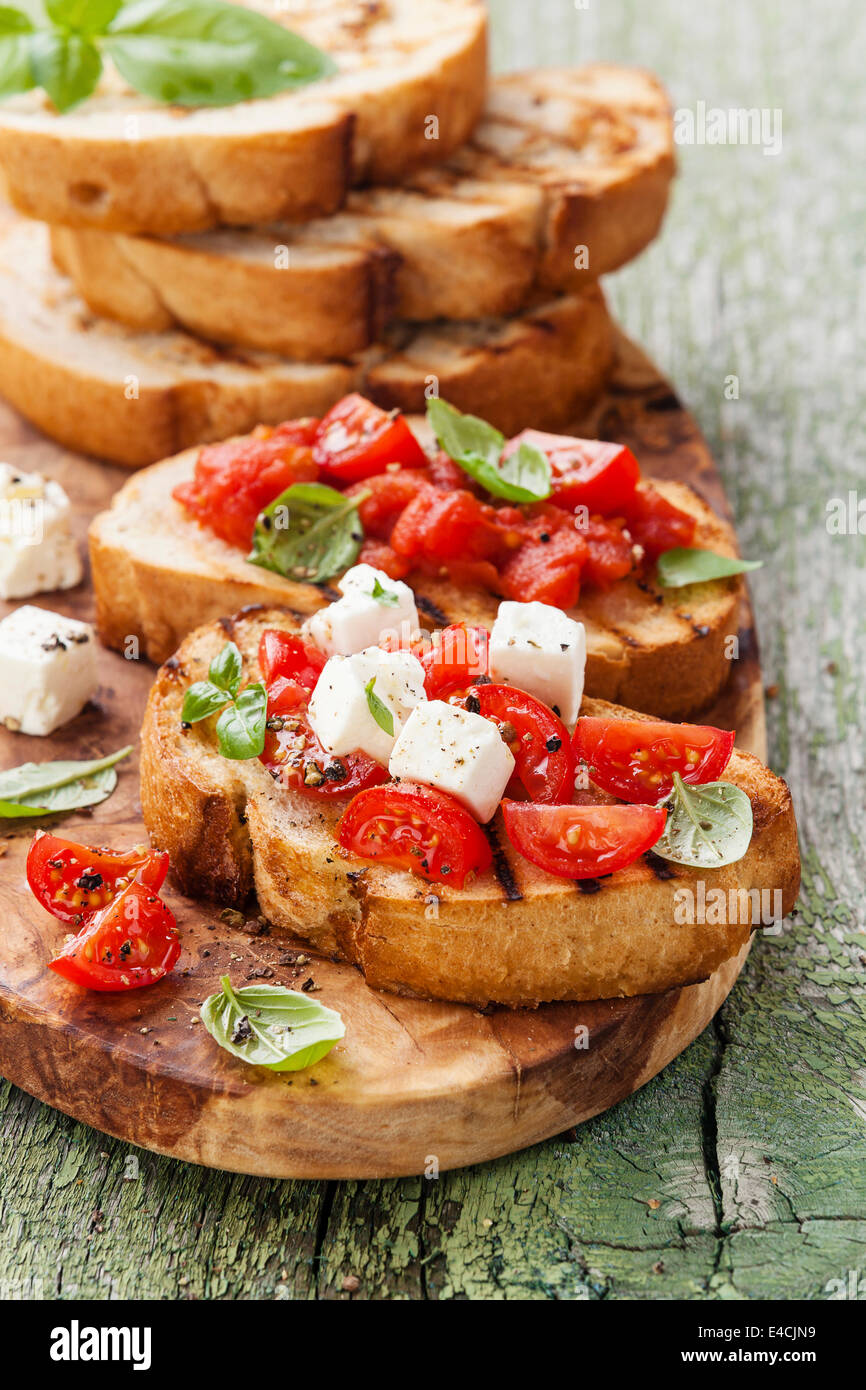 Italian bruschetta con pomodori tritati, il basilico e il formaggio su grigliate di crosta di pane Foto Stock