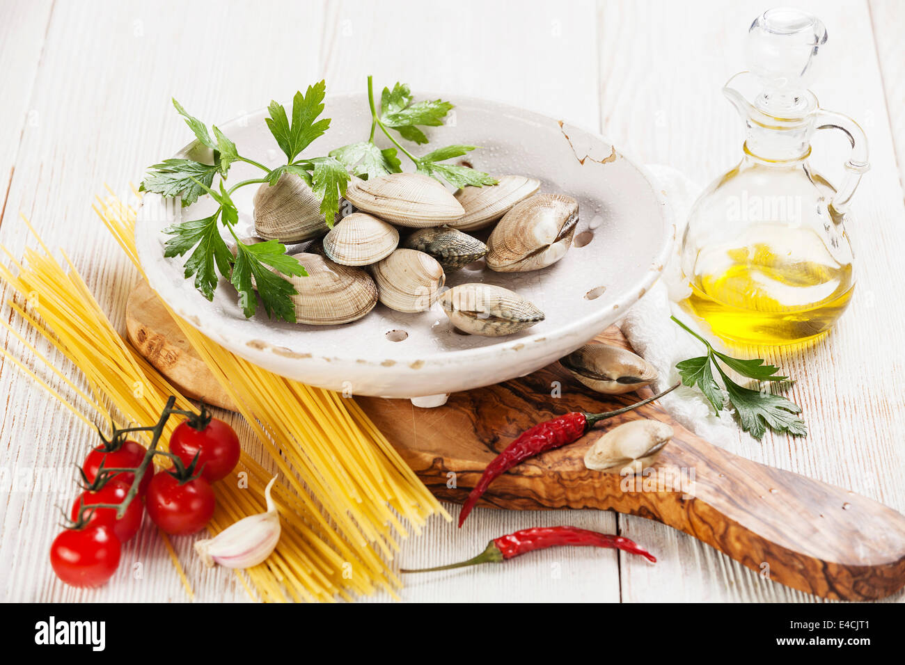 Gli ingredienti per cucinare gli spaghetti vongole gusci vongole, raw spaghetti, prezzemolo in foglie, di pomodori ciliegini Foto Stock