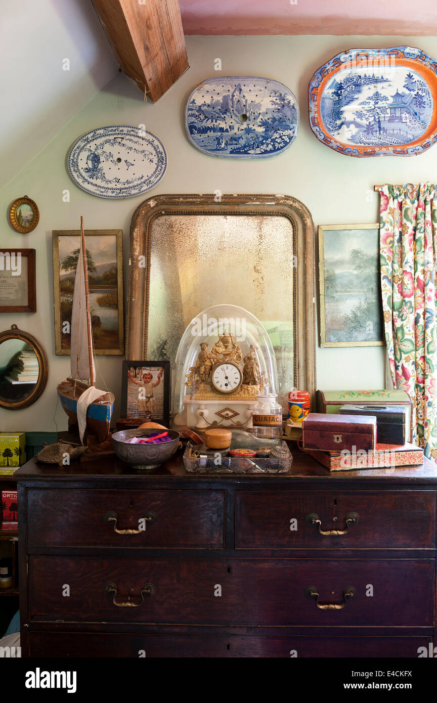 Un antico specchio, modello di barca a vela e vecchie scatole gingillo sulla cassettiera in camera da letto cottage Foto Stock