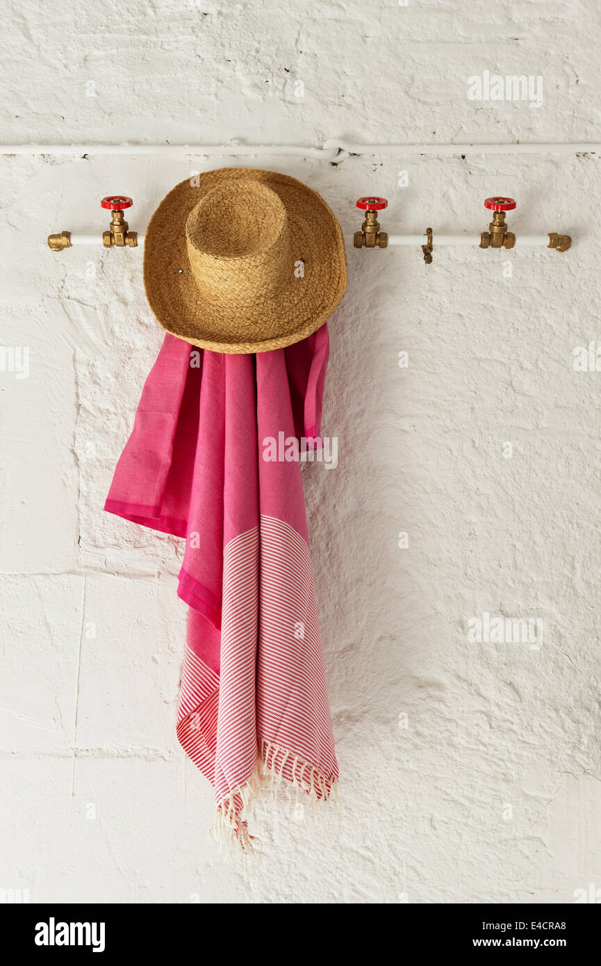 La paglia cappello per il sole e rosa sarong appeso su red valvole utilizzate come picchetti Foto Stock