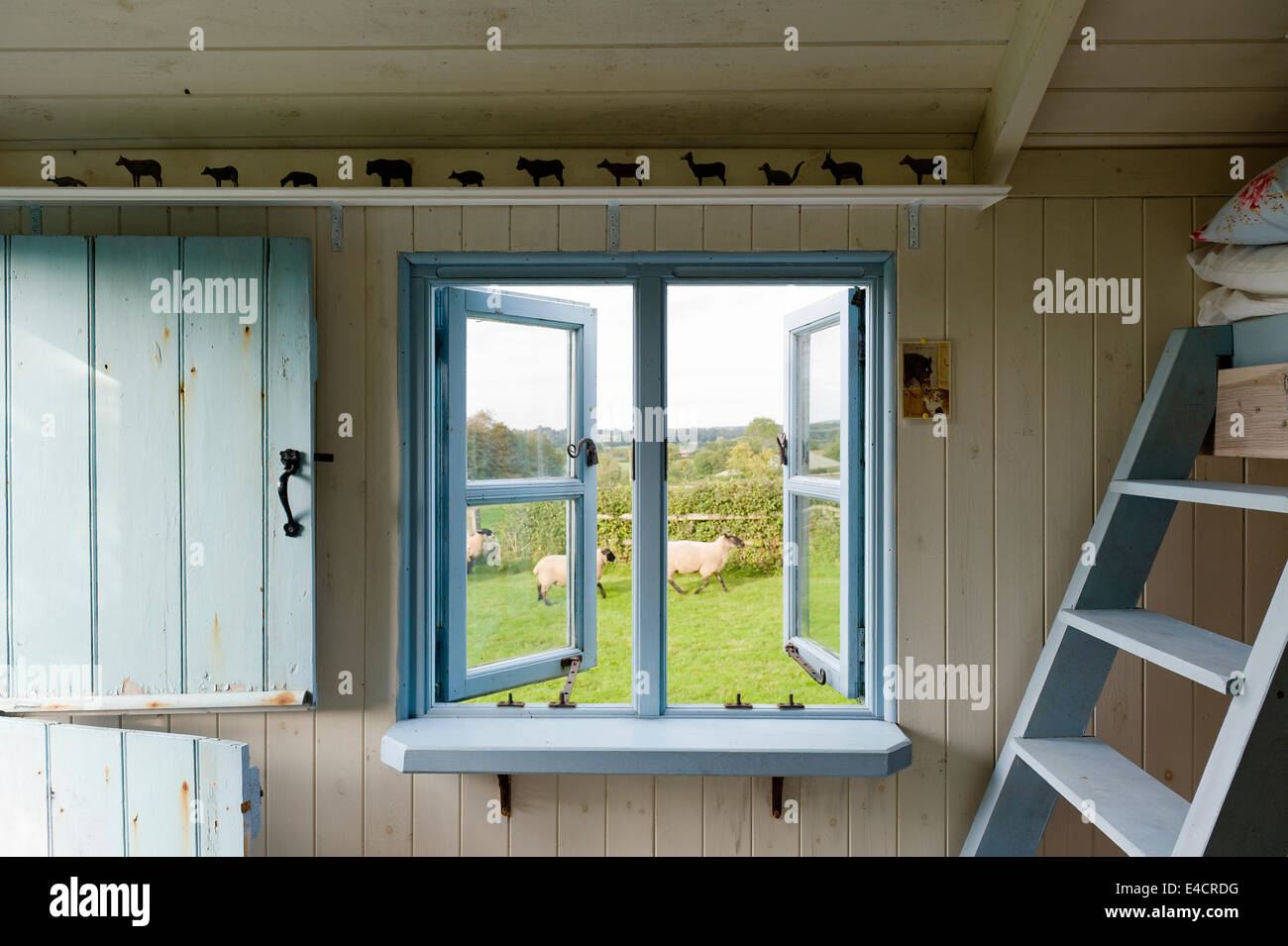 Azzurro incorniciato finestra aperta all'interno di un legno capanna di pastori con abbinamento di blu porta stabile Foto Stock