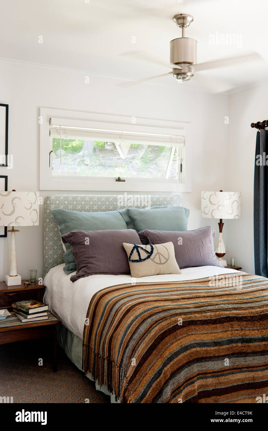 Accogliente camera da letto con strisce di trapunte e cuscini Foto Stock