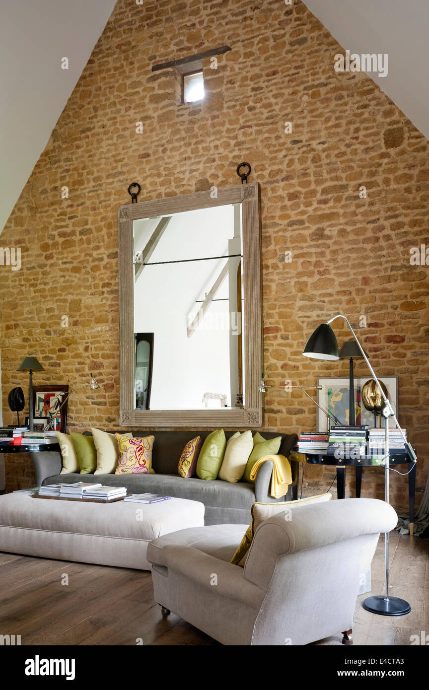 Esposto un muro di mattoni in salotto con soffitto spiovente e un grande specchio Foto Stock