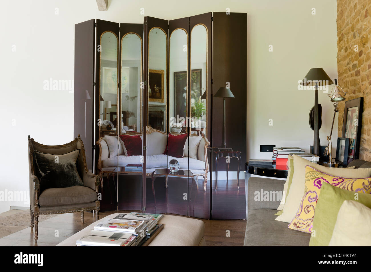 Stampate foto di interni su una schermata di piegatura in soggiorno con mattoni a vista a parete e poltrona Foto Stock