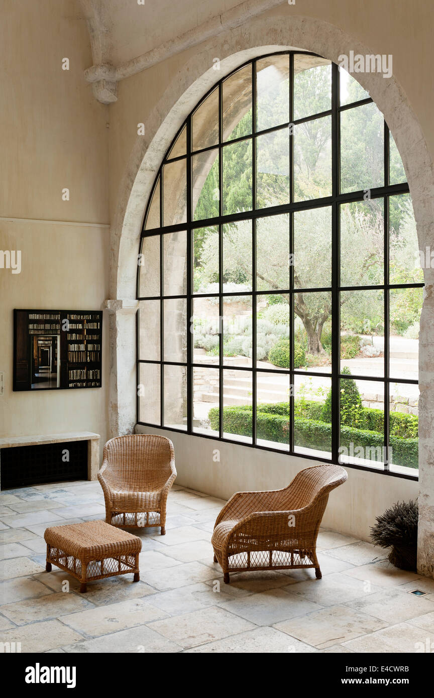 Con pavimenti in pietra in stile galleria spazio con grande finestra ad arco e arredi in vimini Foto Stock