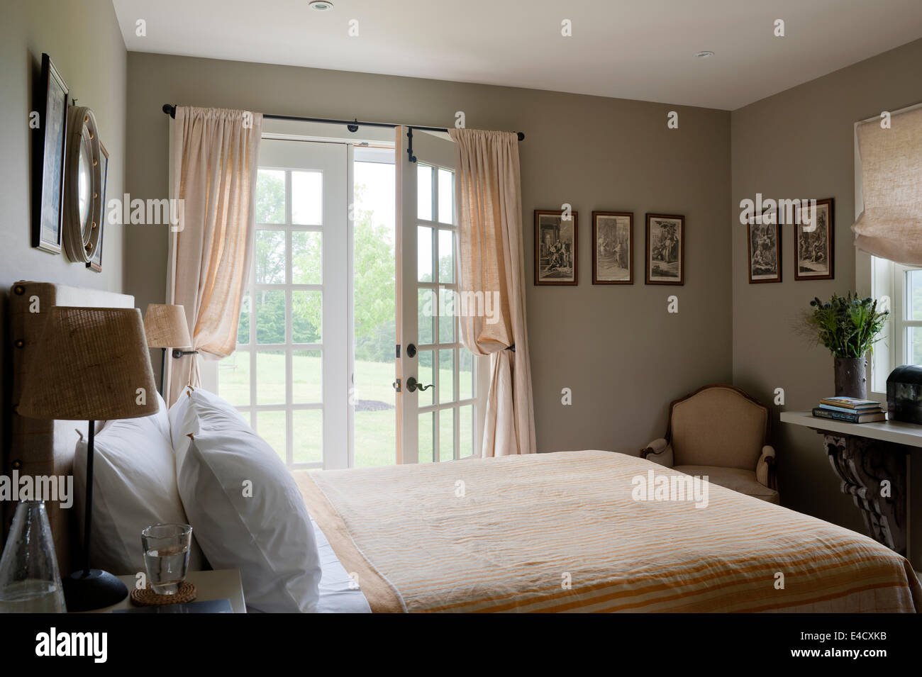 Pesca a strisce bianche e biancheria da letto in camera da letto con finestre francesi Foto Stock