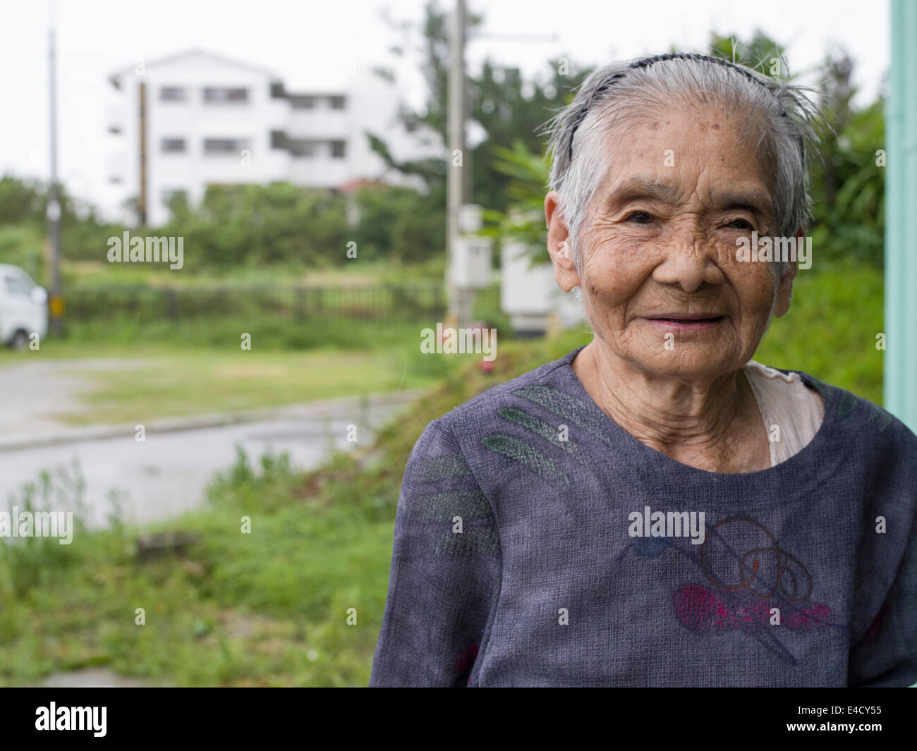 Typhoon Neoguri Okinawa, in Giappone. 9 luglio 2014, le piogge torrenziali e le inondazioni continuano come isole inizia il ripristino. Il 93-anno-vecchio Tokumura san capi fuori dopo il tifone al villaggio ufficio. Lei dice che ha visto grandi tifoni prima. Credito: Chris Willson/Alamy Live News Foto Stock