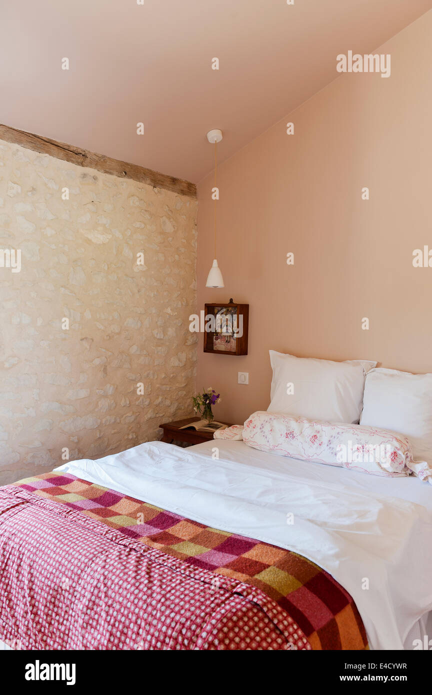 Camera da letto con ruvida parete denocciolate e vintage trapunta letto Foto Stock