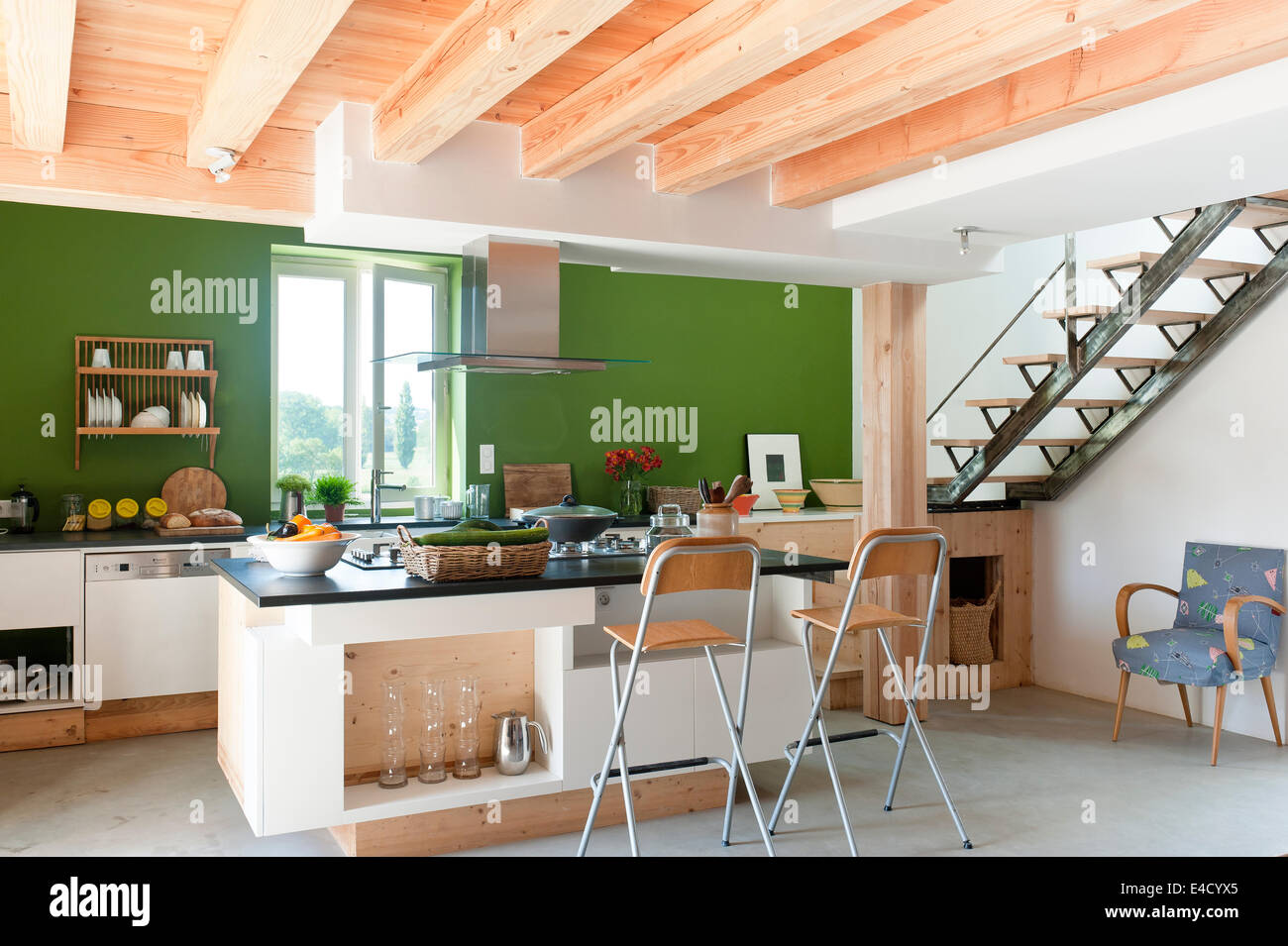 Spazioso e luminoso cucina nella nuova estensione con travi di legno a vista, barra pieghevole sgabelli e isola di cottura Foto Stock