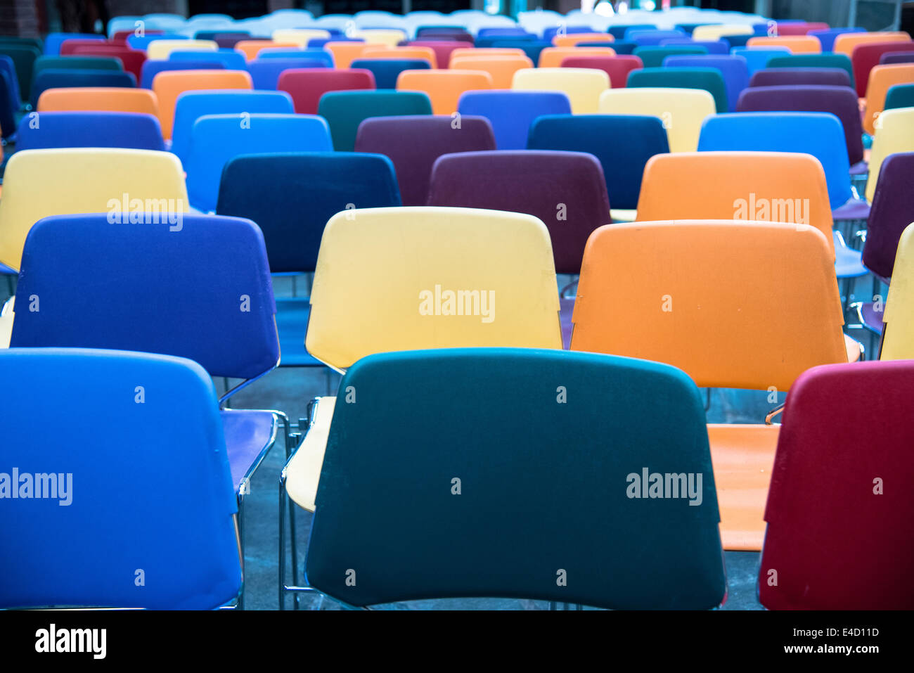 Righe di colorati e svuotare le sedie in plastica in una scuola Foto Stock