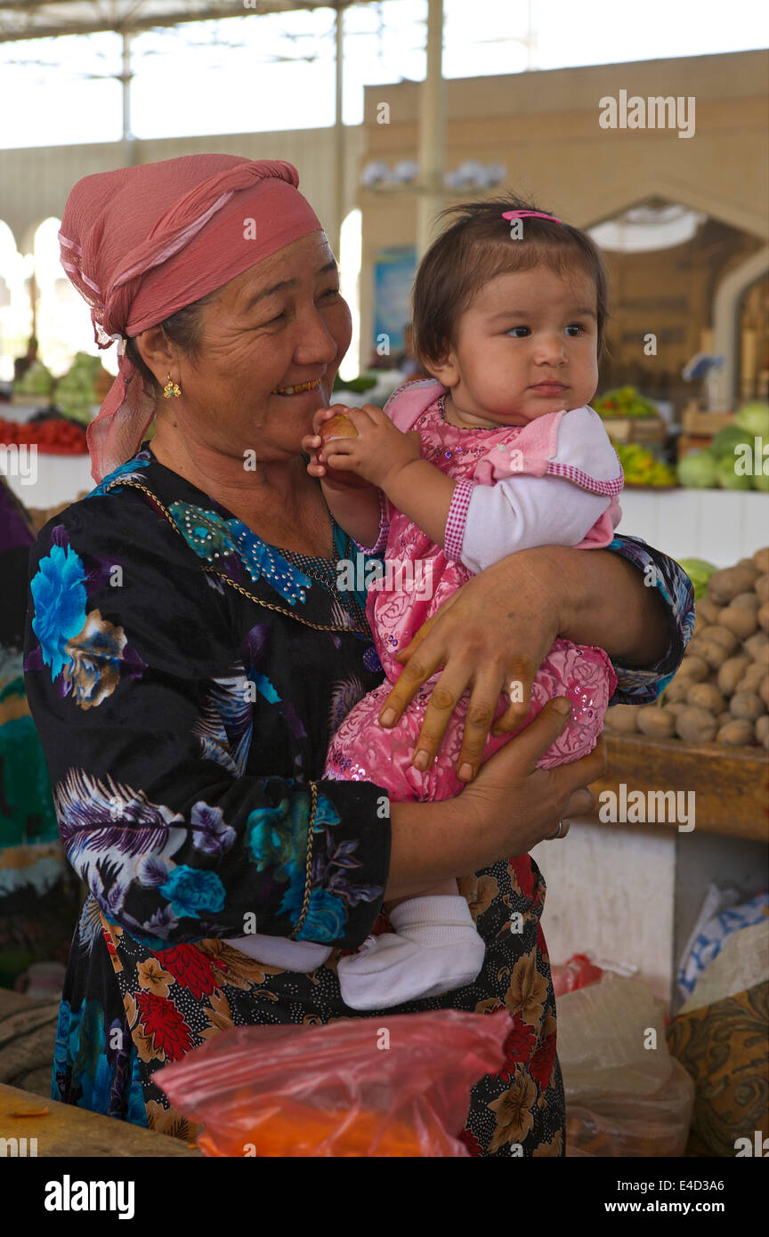 Donna che mantiene una bambina tra le sue braccia, in un bazar, Bukhara, Uzbekistan Foto Stock