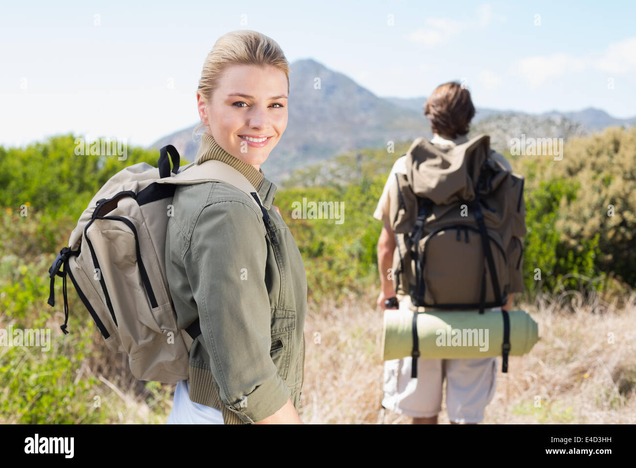 Attraente escursionismo giovane camminando sul sentiero di montagna donna sorridente in telecamera Foto Stock
