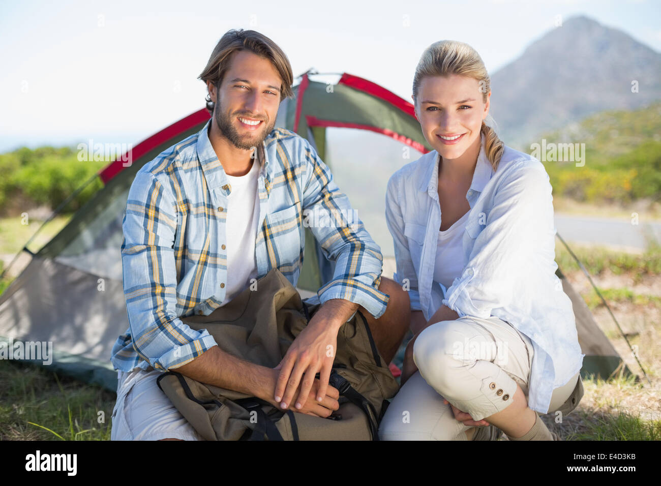 Attraente escursionismo coppia sorridente in telecamera al di fuori della loro tenda Foto Stock
