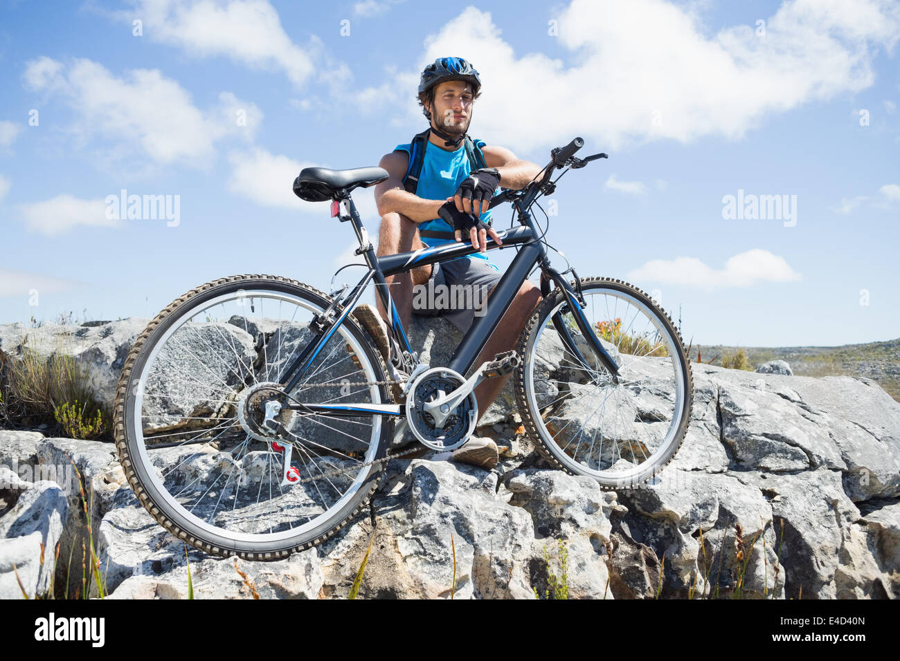 Montare il ciclista prendendo una pausa sul picco roccioso Foto Stock