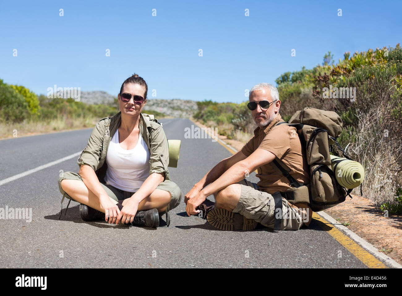 Il sollevatore escursionismo coppia seduta sul lato della strada a guardare la fotocamera Foto Stock