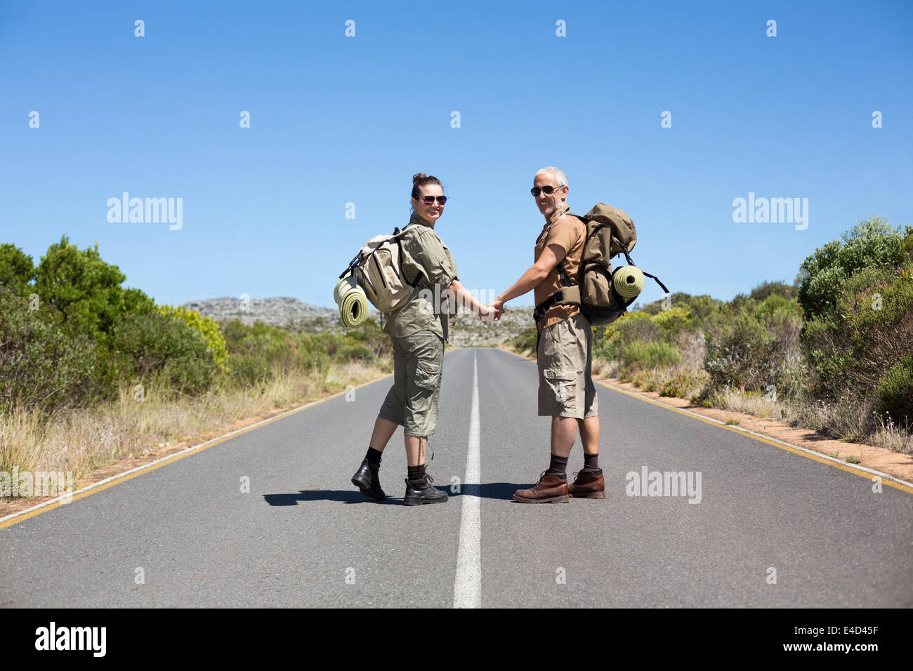 Il sollevatore escursionismo coppia tenendo le mani sulla strada sorridente in telecamera Foto Stock
