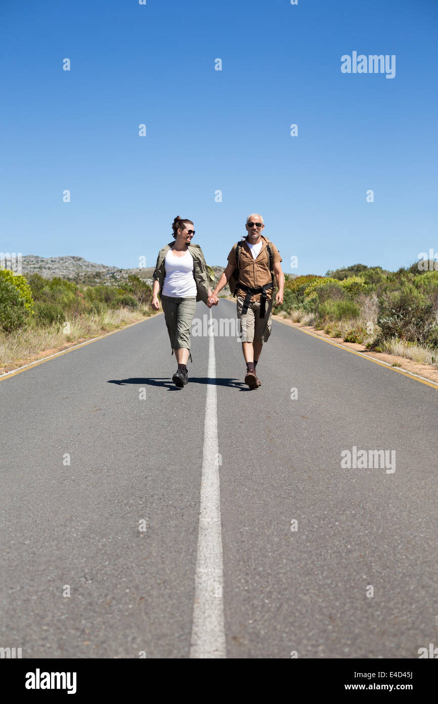 Il sollevatore escursionismo coppia tenendo le mani sulla strada sorridente in telecamera Foto Stock