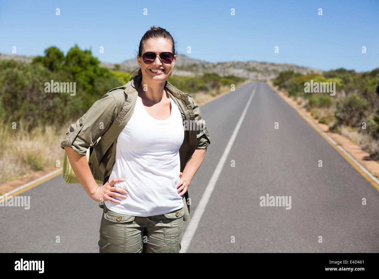 Piuttosto escursionista permanente sulla strada e sorridente in telecamera Foto Stock