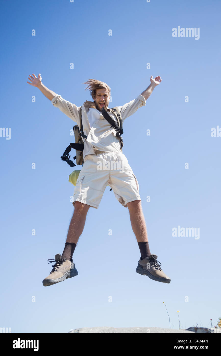 Bello escursionista jumping al vertice sorridente in telecamera Foto Stock