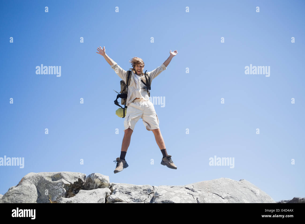 Bello escursionista jumping al vertice sorridente in telecamera Foto Stock