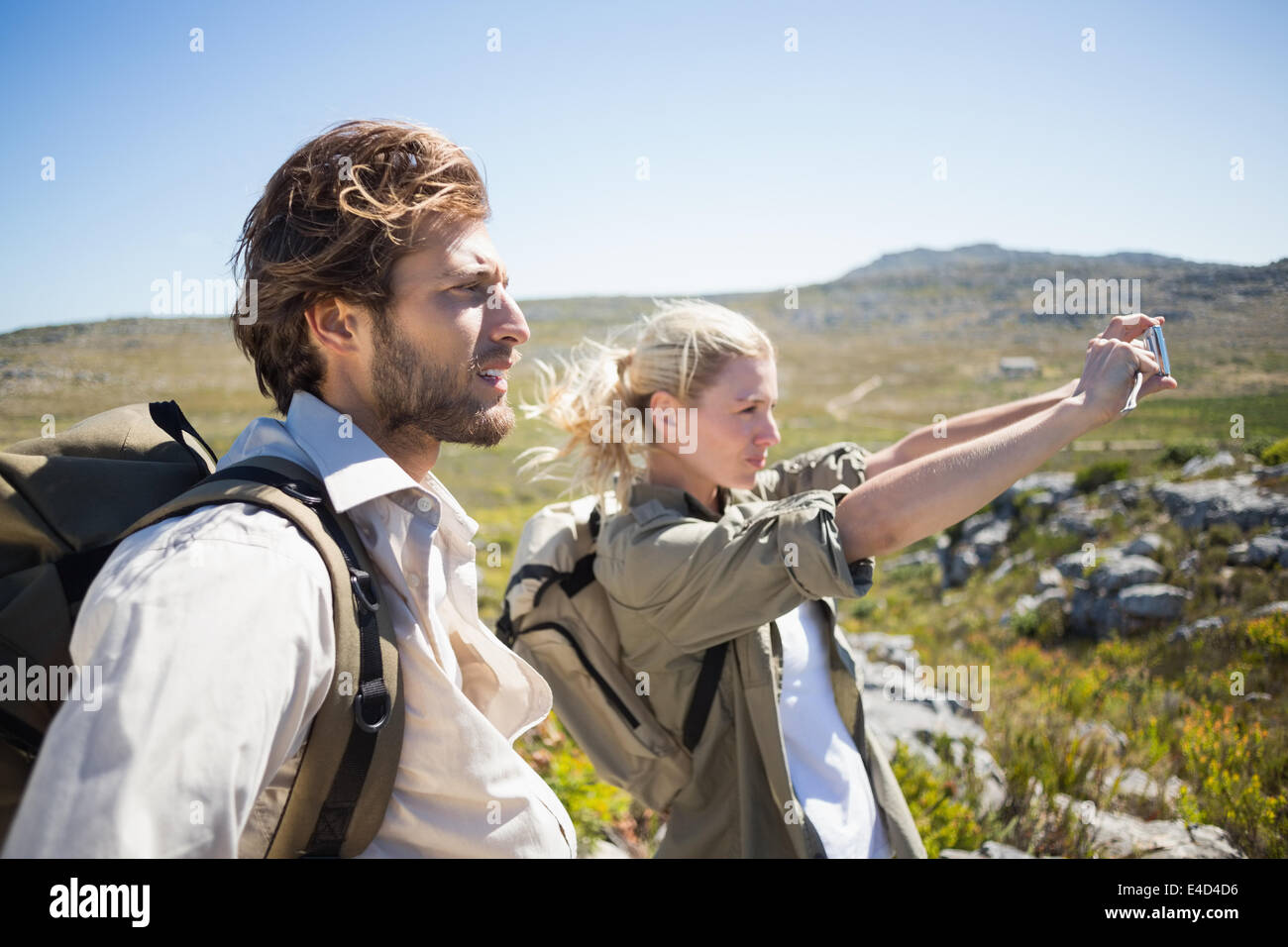 Escursionismo giovane in piedi sul terreno di montagna prendendo un selfie Foto Stock