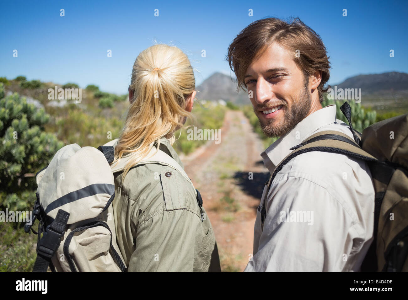 Escursionismo giovane camminando sul terreno di montagna uomo sorridente in telecamera Foto Stock