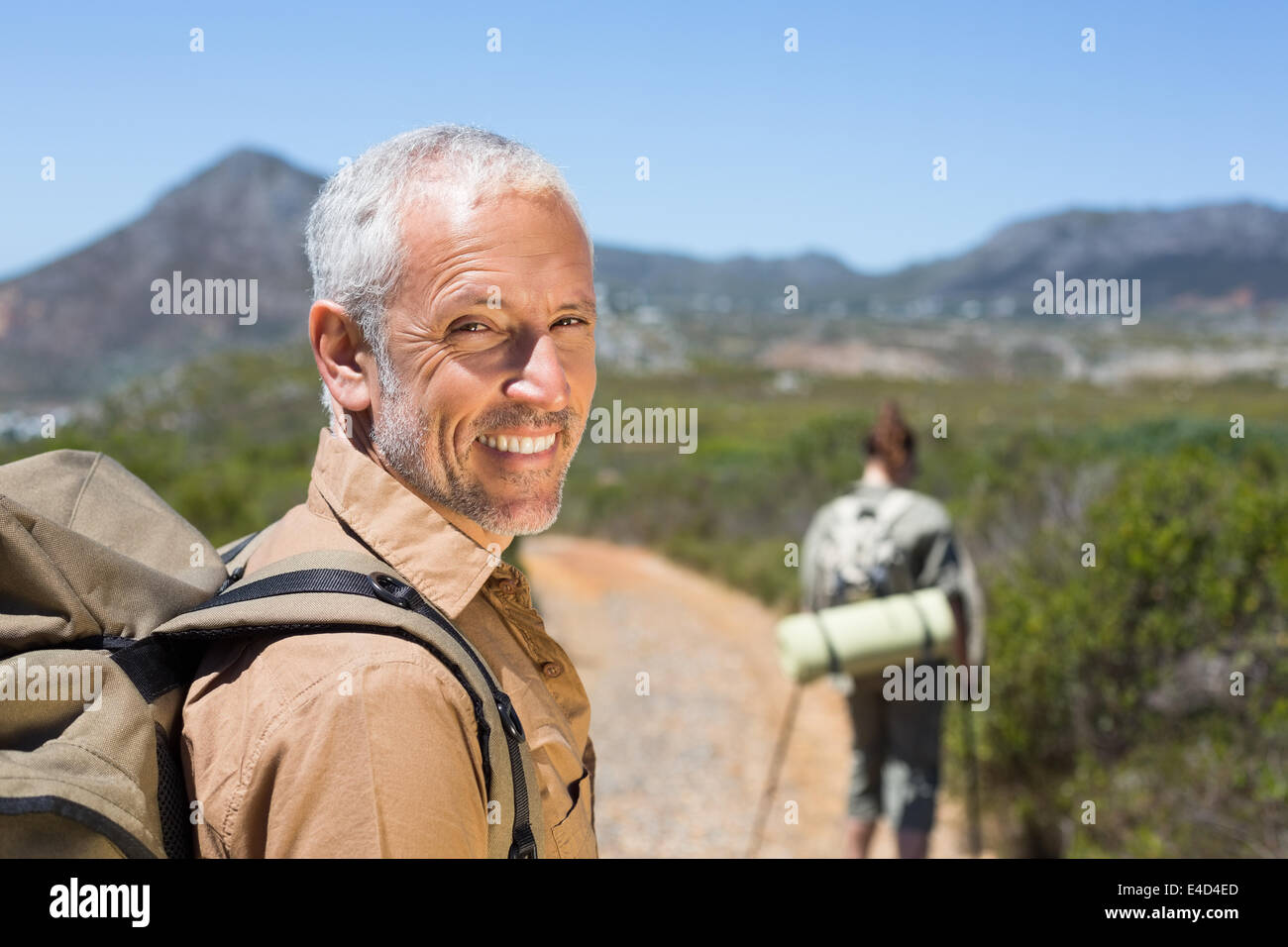 Escursionismo giovane camminando sul sentiero di montagna uomo sorridente in telecamera Foto Stock