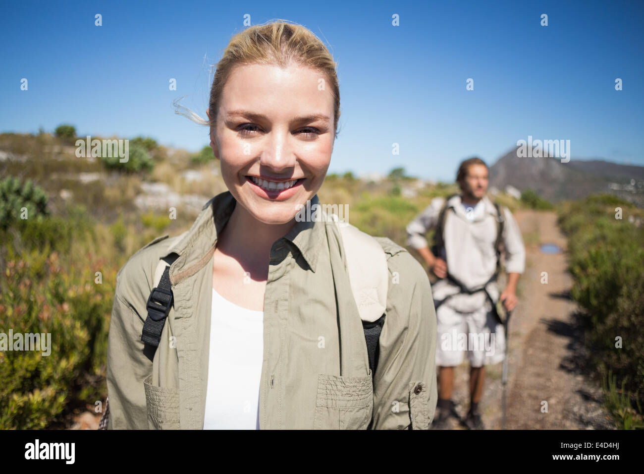 Escursionismo giovane camminando sul terreno di montagna donna sorridente in telecamera Foto Stock