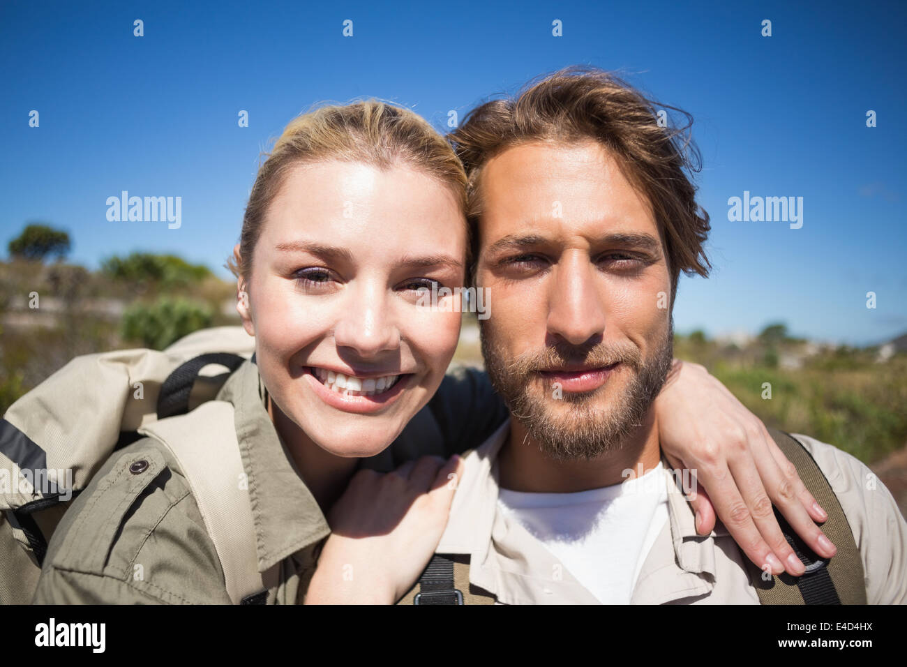 Felice coppia trekking a piedi su terreno di montagna sorridente in telecamera Foto Stock