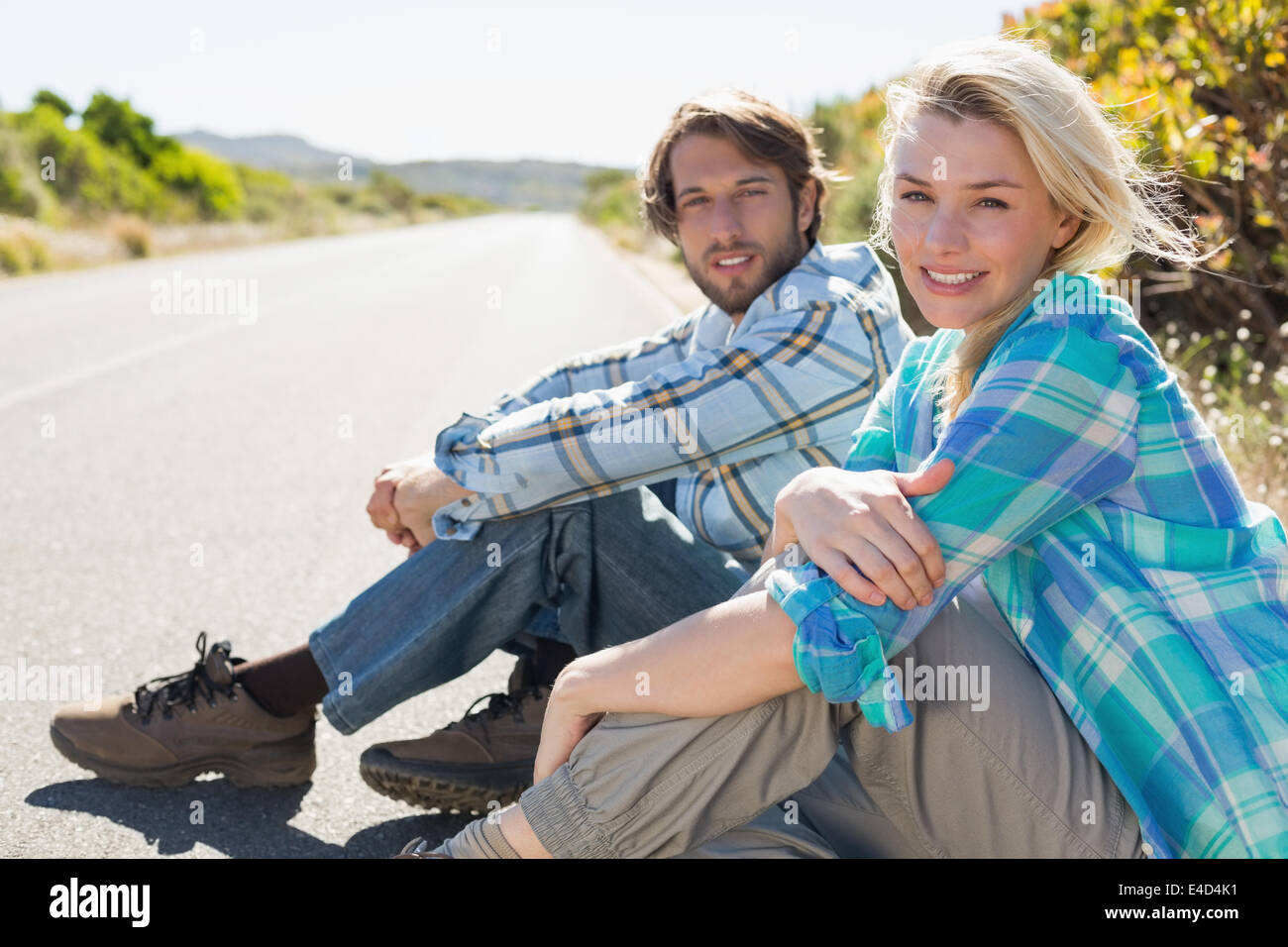 Coppia attraente seduti sulla strada sorridente in telecamera Foto Stock