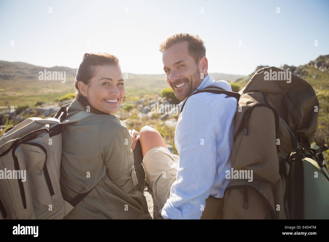 Escursionismo coppia seduta sul terreno di montagna sorridente in telecamera Foto Stock